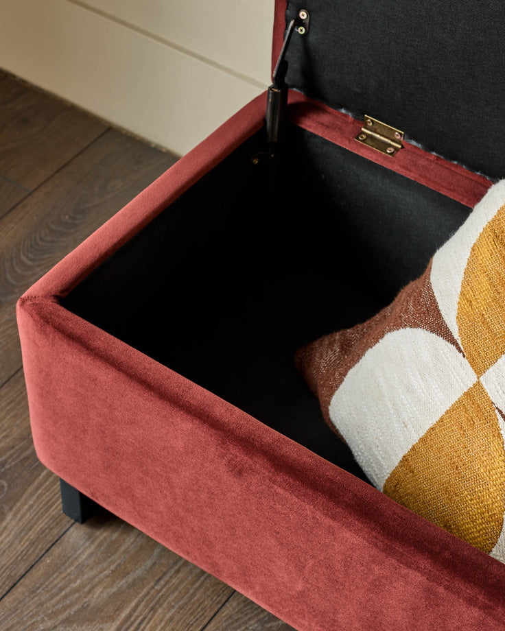 Amalfi velvet ottoman bench in toffee red with open storage compartment, showing black interior and brass hardware detail.