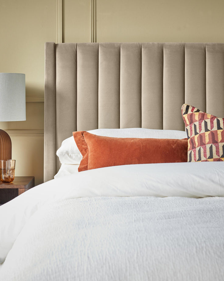 Bedroom scene showcasing a modern headboard and stylish scatter cushions atop a crisp, white duvet cover.