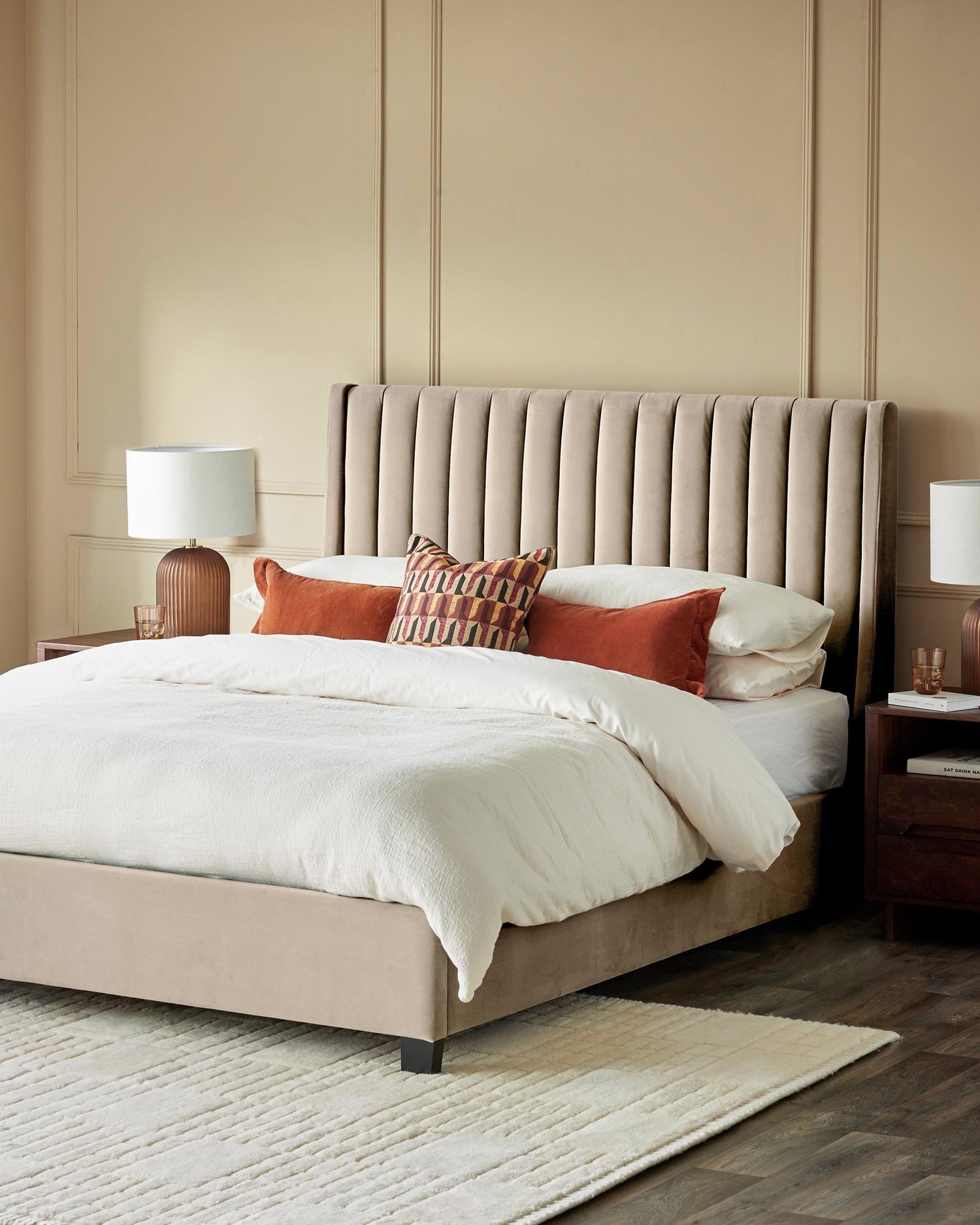 Bedroom featuring a stylish upholstered bed with headboard, bedside tables with lamps and a neutral rug.