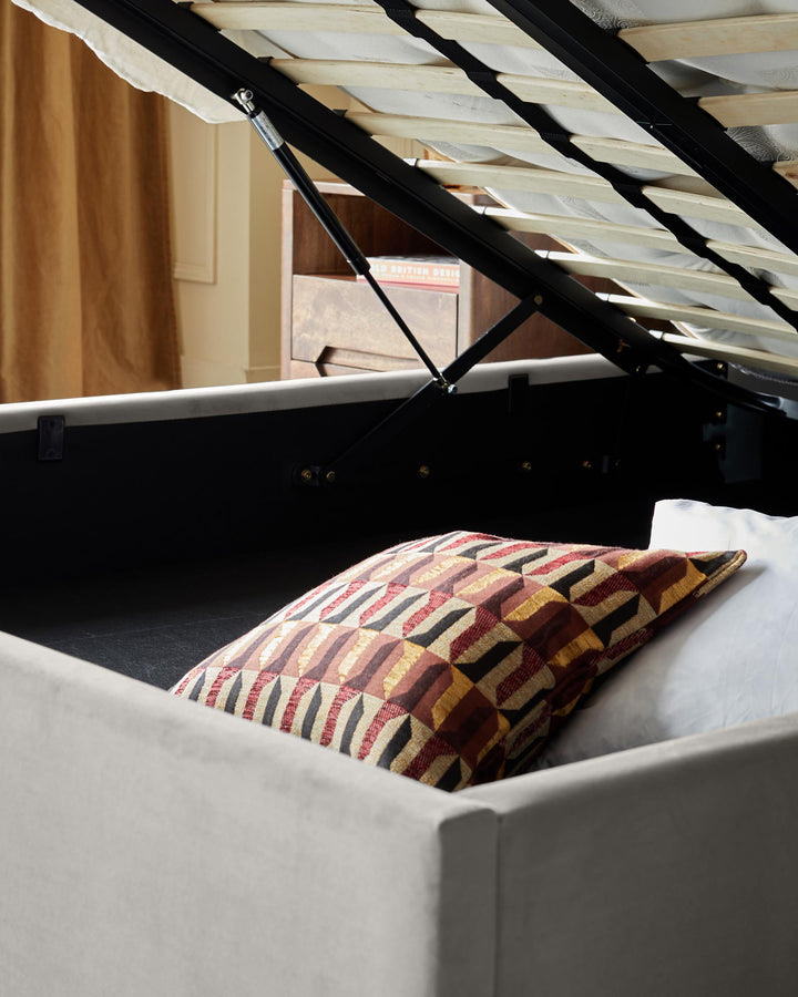 Storage bed with lift-up base, revealing bedding. Stylish and functional for bedroom organisation.