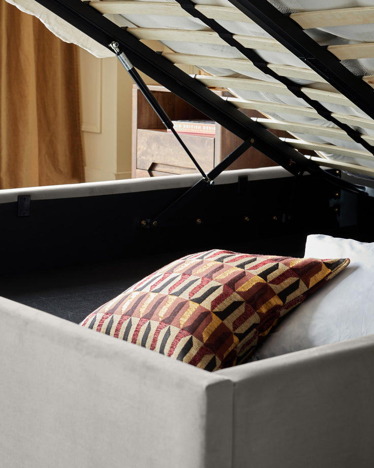 Storage bed with lift-up base, revealing bedding. Stylish and functional for bedroom organisation.