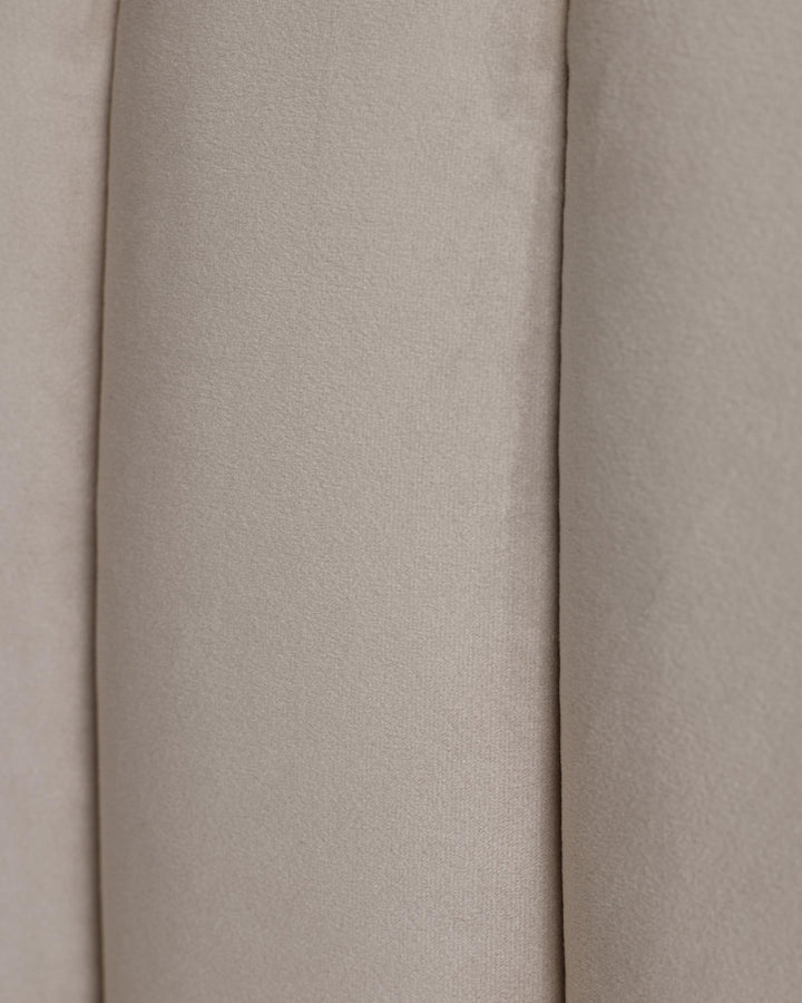 Close-up of light beige fabric headboard with channel tufting. Soft, neutral colour and texture.