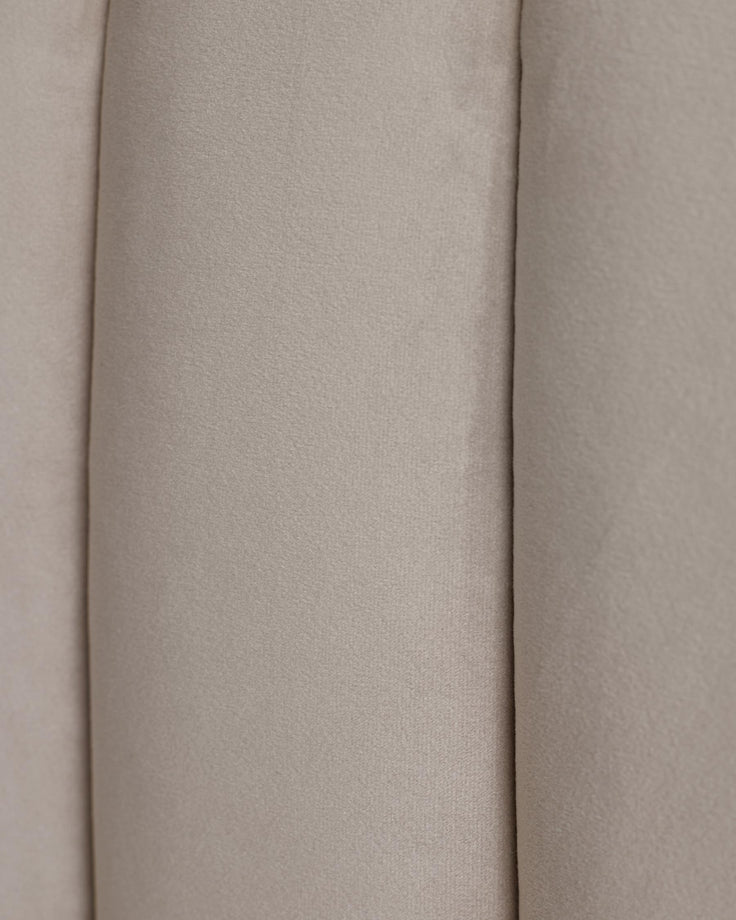 Close-up of light beige fabric headboard with channel tufting. Soft, neutral colour and texture.