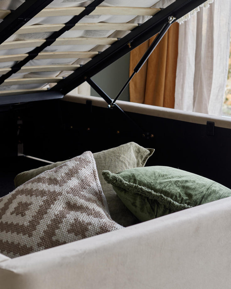 Storage bed with cushions inside. The bed frame is upholstered with light grey fabric, and the bed mechanism is black metal.