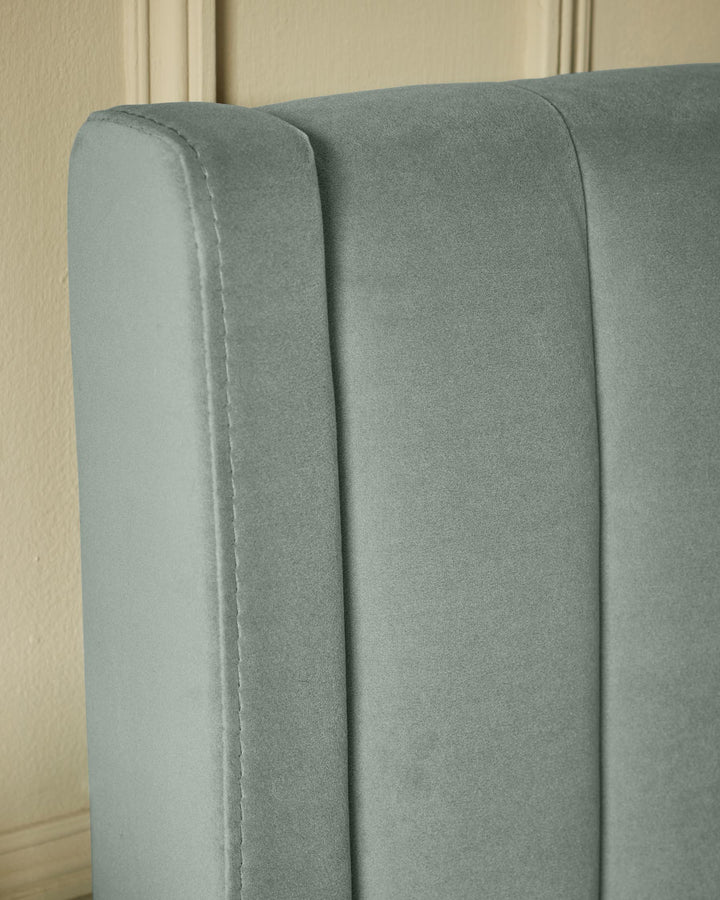 Close-up of a grey velvet headboard, featuring a panelled design and a smooth, plush texture.