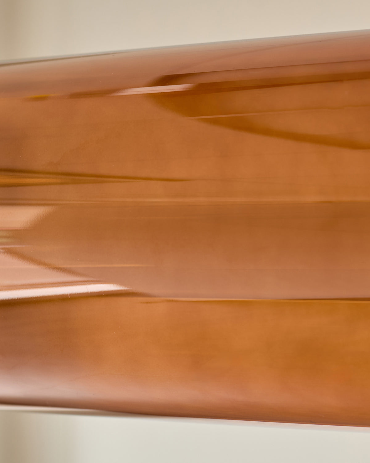 Amber single pendant light with caramel glass, close-up detail shot showing smooth curved glass surface and glossy finish.