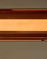 Amber single pendant light with caramel glass shade, shown in close-up detail against neutral background.