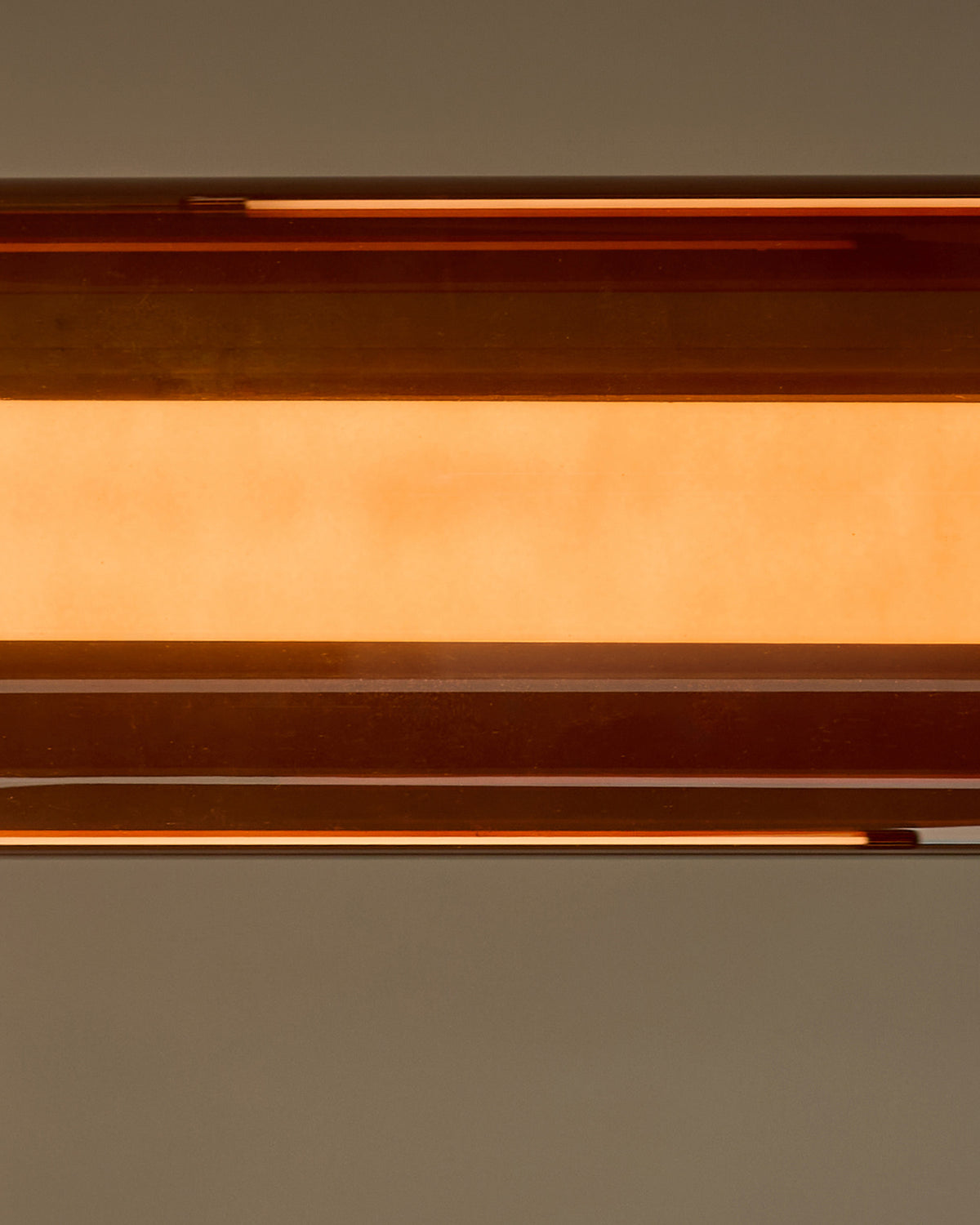 Amber single pendant light with caramel glass shade, shown in close-up detail against neutral background.