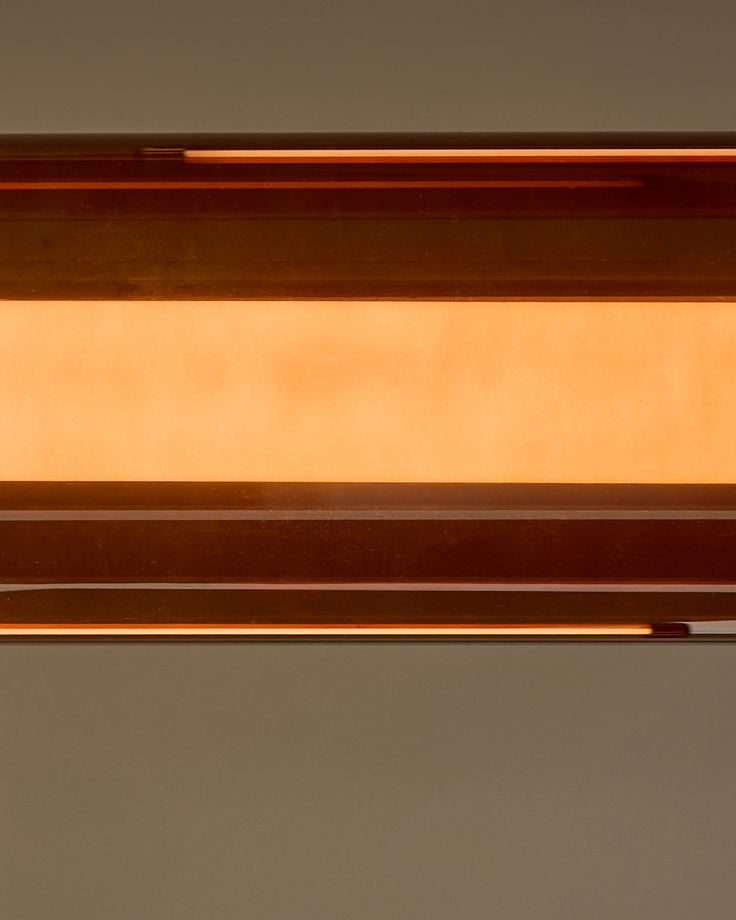 Amber single pendant light with caramel glass shade, shown in close-up detail against neutral background.