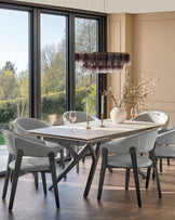Amelia dining chair in light grey leather with black wooden legs, shown at a dining table in a modern dining room.