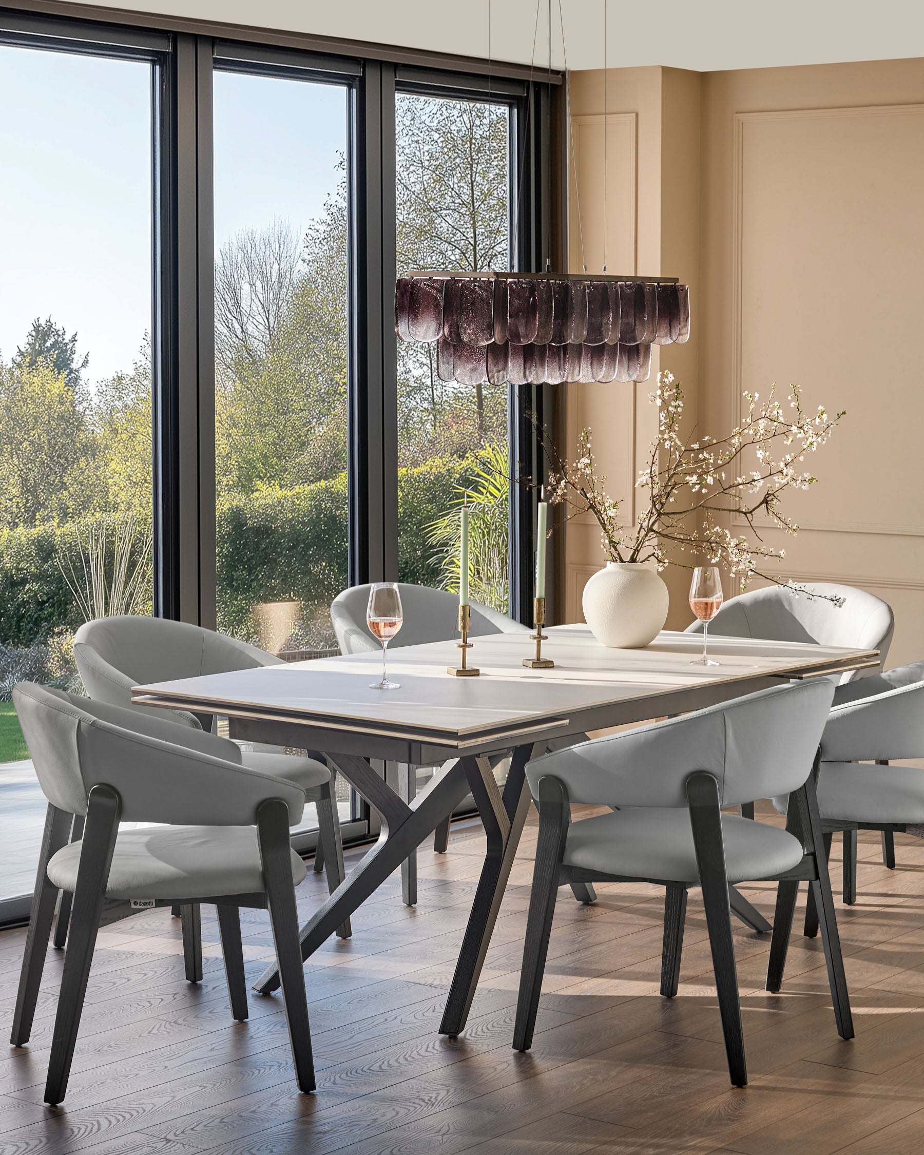 Amelia dining chair in light grey leather with black wooden legs, shown at a dining table in a modern dining room.