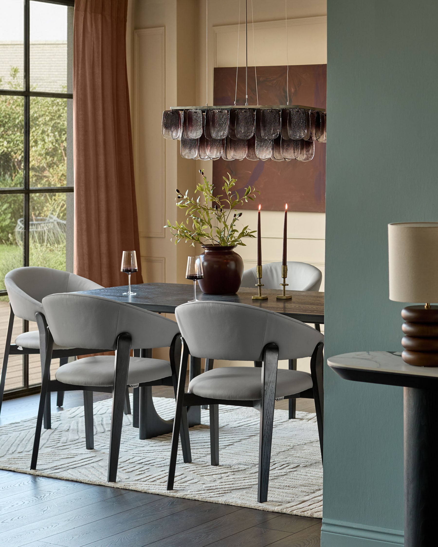 Amelia dining chair in light grey leather with black wood frame, shown in modern dining room setting.