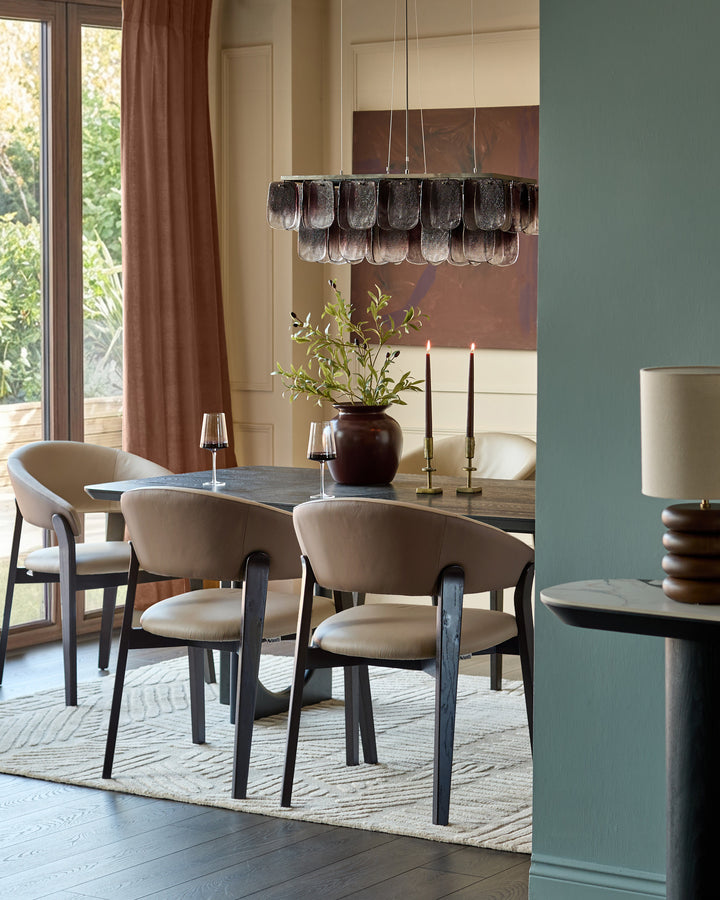 Amelia dining chair in natural leather with mocha wood frame, shown at dining table in elegant room setting.