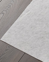 Close-up of grey laminate flooring and a white felt pad. Ideal for underlay or soundproofing, with a modern feel.