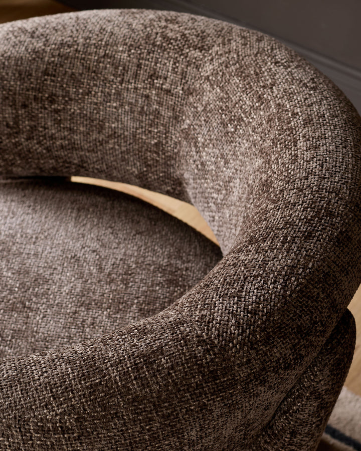 Anya accent chair in mocha fabric, close-up detail showing curved armrest and woven textile texture.