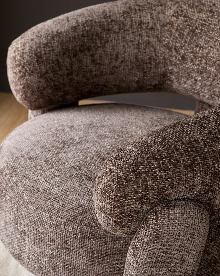 Anya accent chair in mocha fabric, close-up detail showing curved armrest and plush upholstery texture.