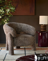 Anya accent chair in mocha fabric with curved barrel shape and sturdy legs in a styled living room setting.