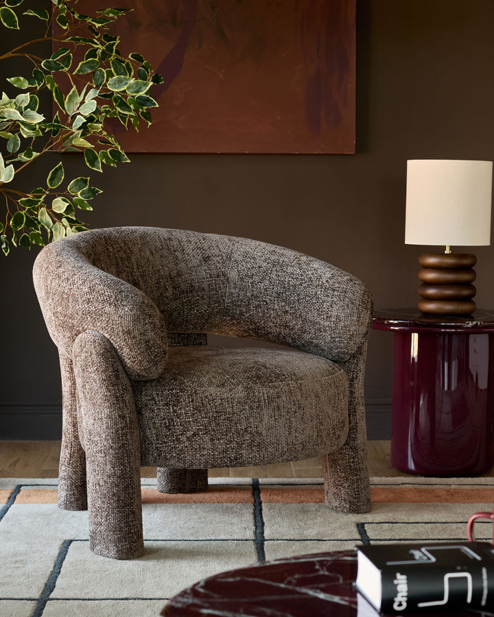 Anya accent chair in mocha fabric with curved barrel shape and sturdy legs in a styled living room setting.