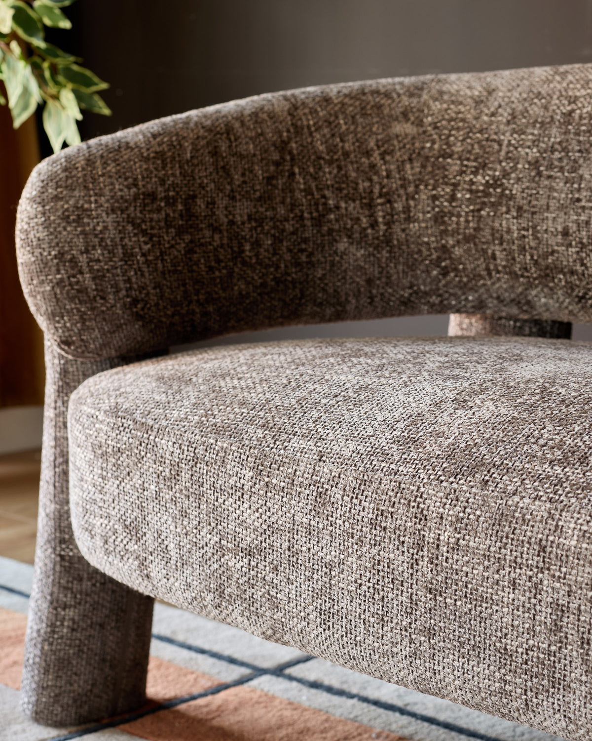 Anya accent sofa in mocha fabric, showing curved armrest and seat detail from side angle.