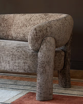 Anya accent sofa in mocha fabric, close-up detail of rolled arm and cylindrical leg on colorful area rug.