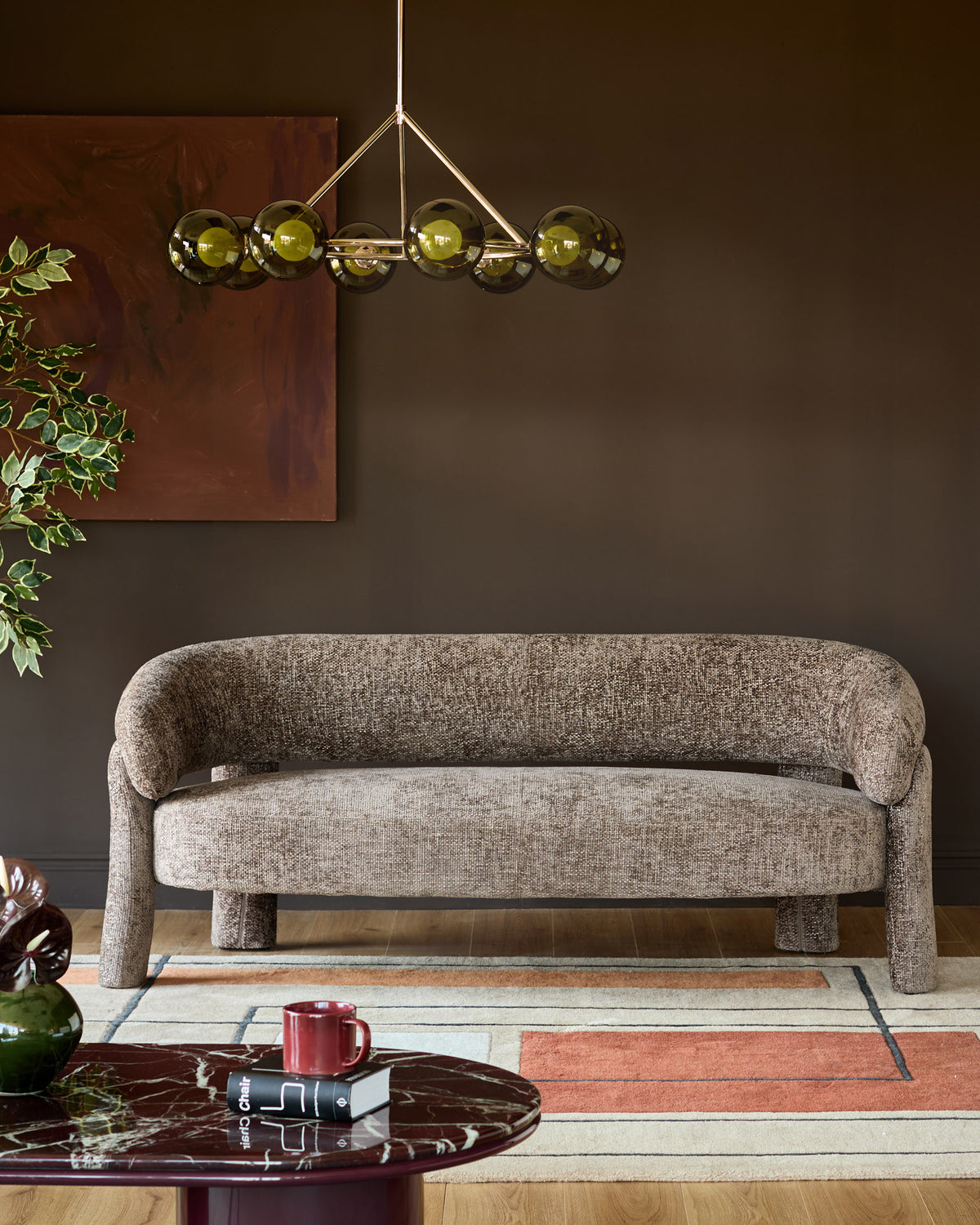 Mocha fabric accent sofa with curved arms and cylindrical legs in a styled living room setting.