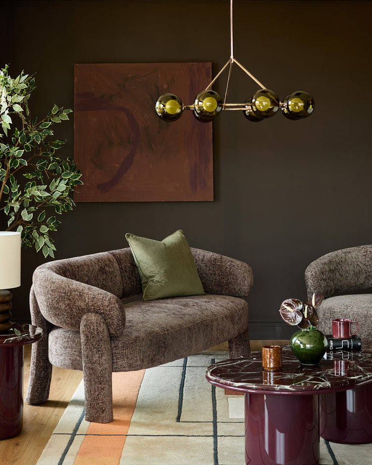 Mocha fabric accent sofa with curved arms and legs in a styled living room setting.