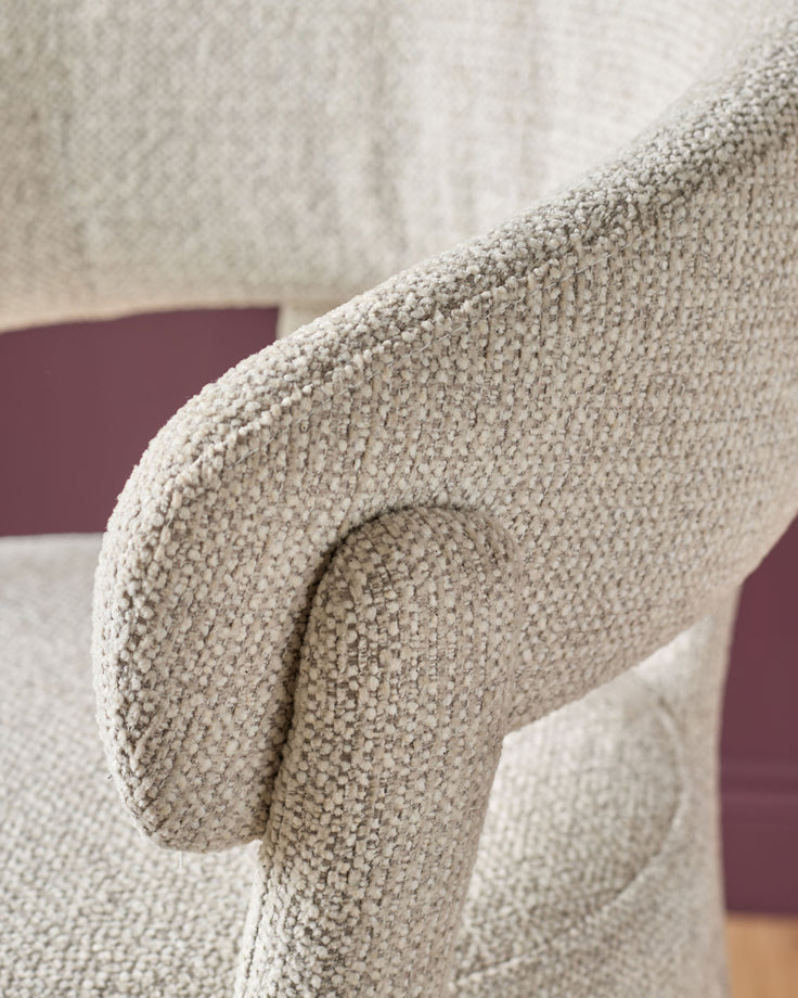 Anya bar stool in natural fabric, close-up of curved armrest detail and woven textile texture.