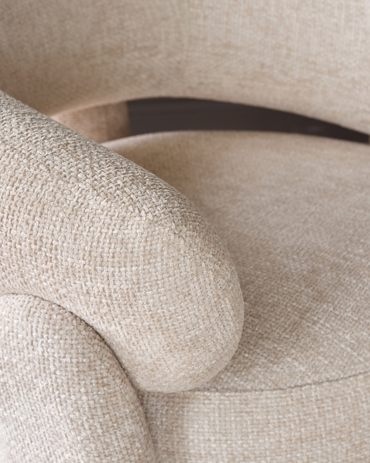 Anya accent chair in natural fabric, close-up of rolled arm and metal frame detail.