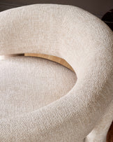 Anya accent chair in natural fabric, close-up of curved backrest and wooden handle detail.