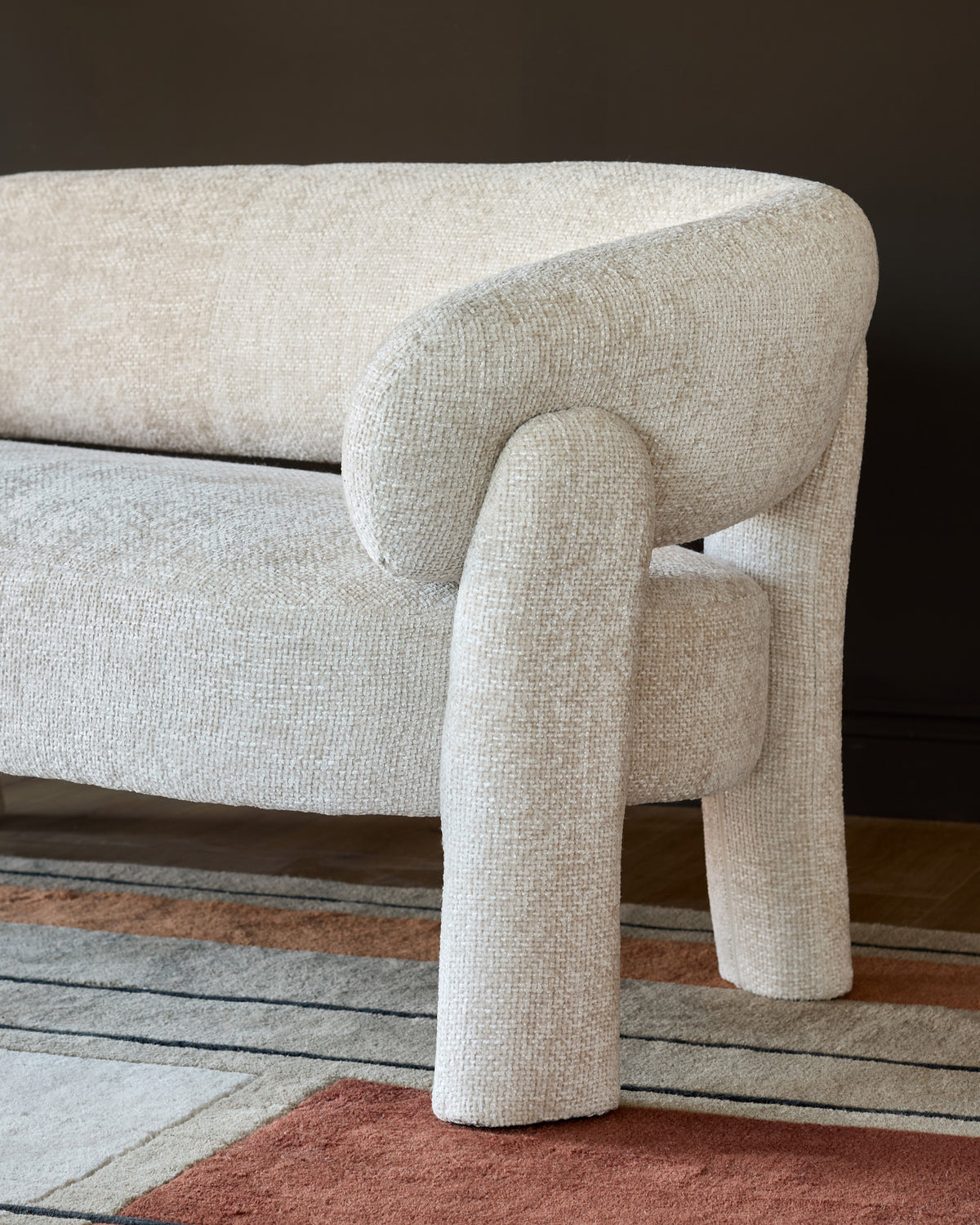 Anya accent sofa in natural fabric, showing curved armrest and leg detail from side angle.