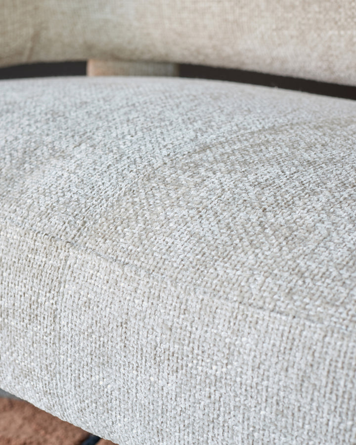 Close-up of natural beige fabric on Anya accent sofa, showing textured weave and curved armrest detail.