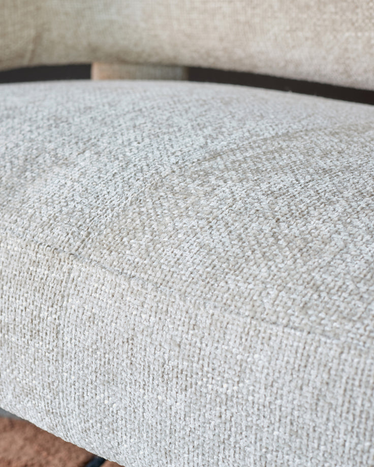 Close-up of natural beige fabric on Anya accent sofa, showing textured weave and curved armrest detail.