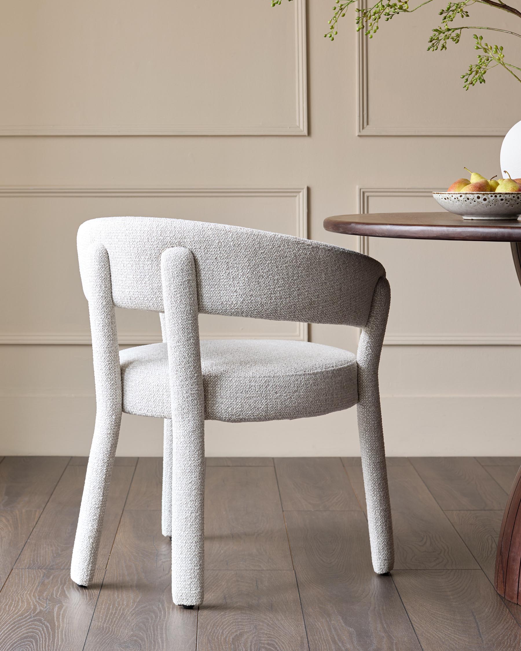 A grey upholstered chair sits by a wooden table, offering a stylish and comfy spot to relax.