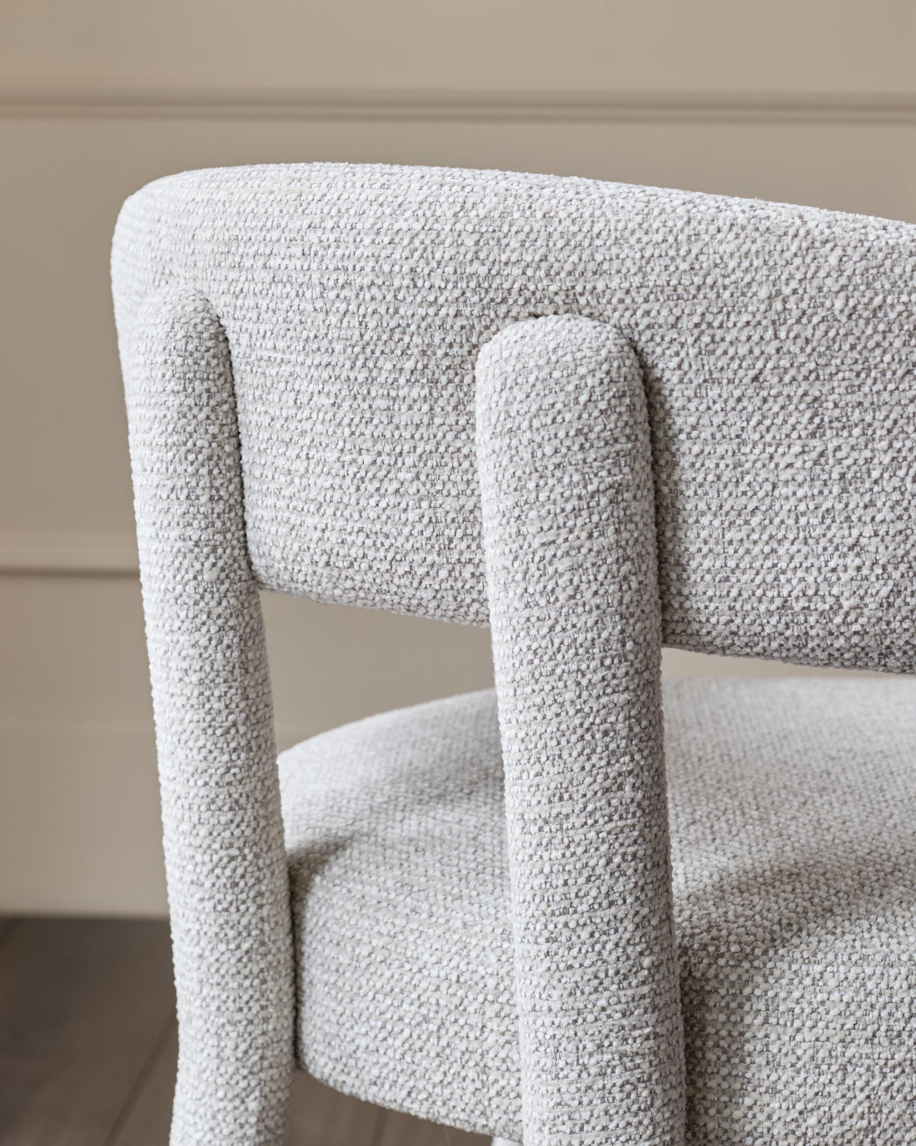 Close-up of a stylish grey boucle chair, showcasing its texture and modern design. A comfortable and elegant seating option.