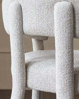 Close-up of an upholstered chair, showing the texture of the fabric and the curved shape of the frame.