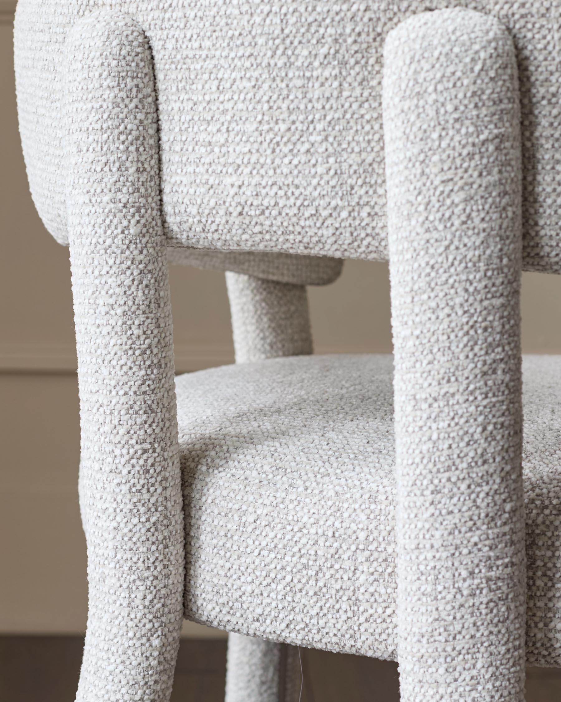 Close-up of an upholstered chair, showing the texture of the fabric and the curved shape of the frame.