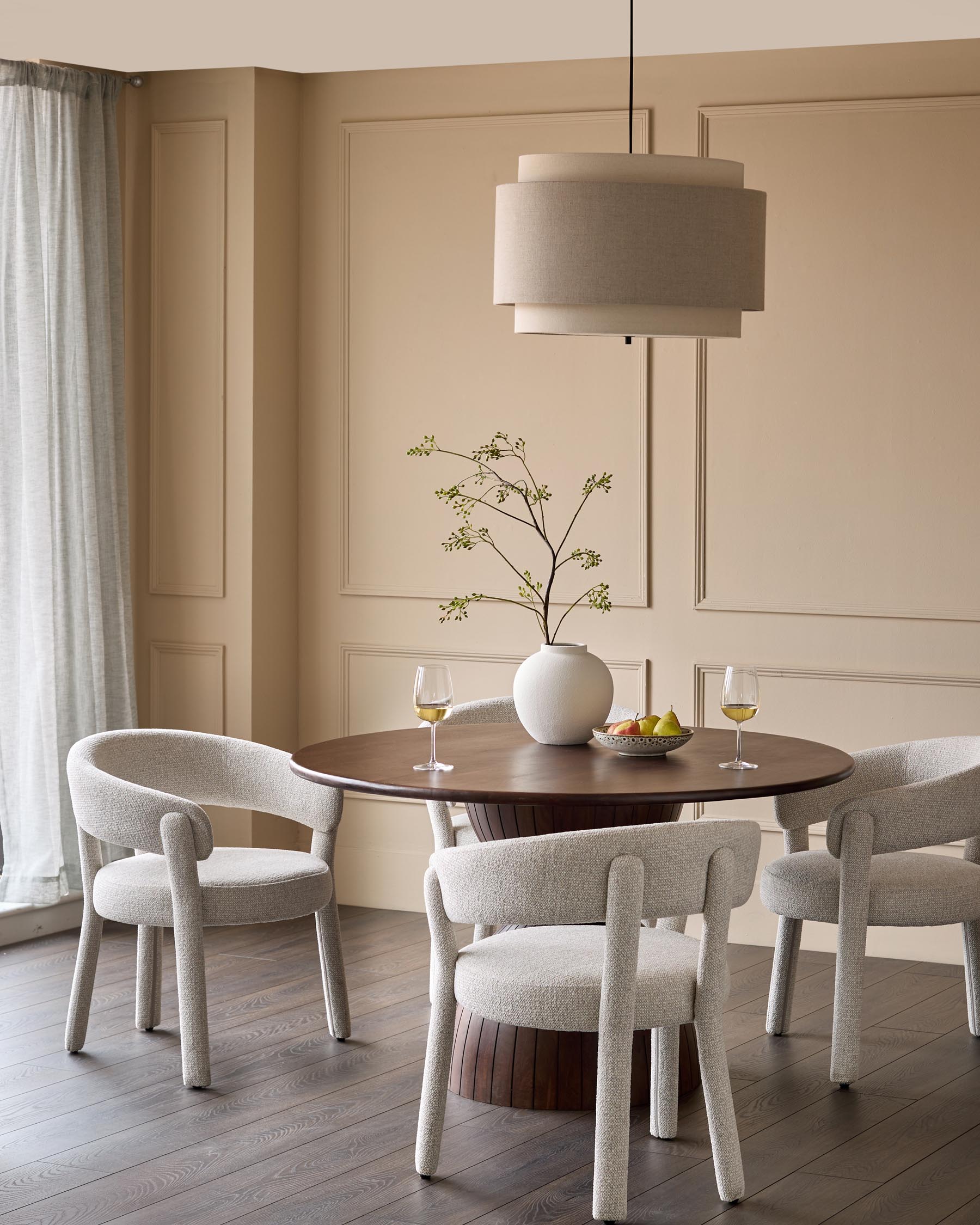 A modern dining set featuring a round table, stylish chairs, and a chic pendant light, set against a neutral backdrop.