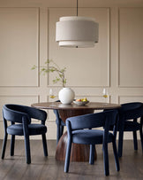 A round wood dining table with 4 upholstered chairs and a large drum pendant light create a stylish dining space.
