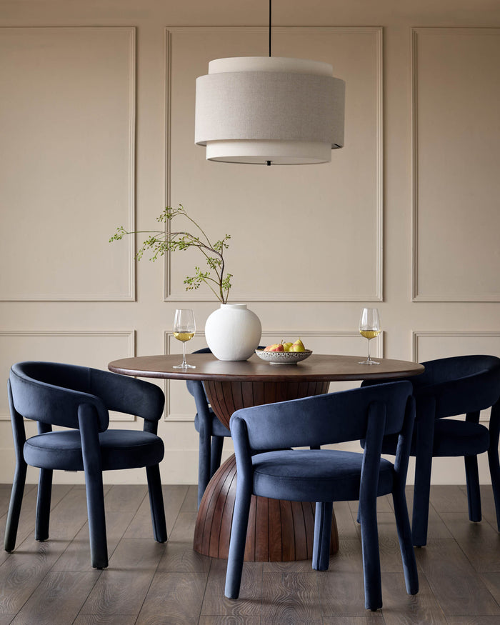 A round wood dining table with 4 upholstered chairs and a large drum pendant light create a stylish dining space.