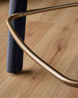Anya bar stool velvet dark navy - close-up of curved brass handle and leg against wooden floor.