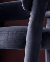 Dark navy velvet Anya bar stool, close-up of backrest and armrest showing soft fabric texture and wooden frame detail.