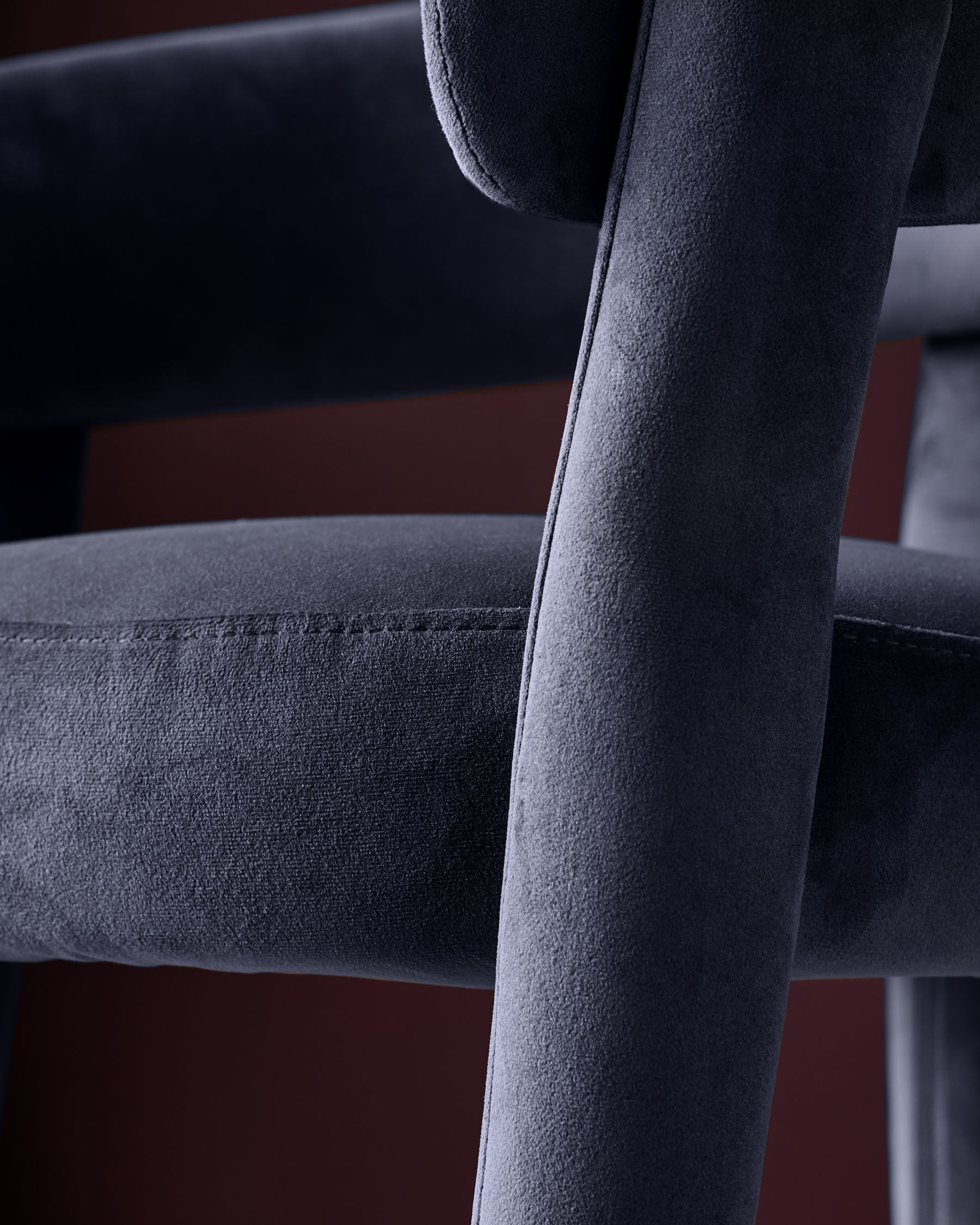 Dark navy velvet Anya bar stool, close-up of backrest and armrest showing soft fabric texture and wooden frame detail.