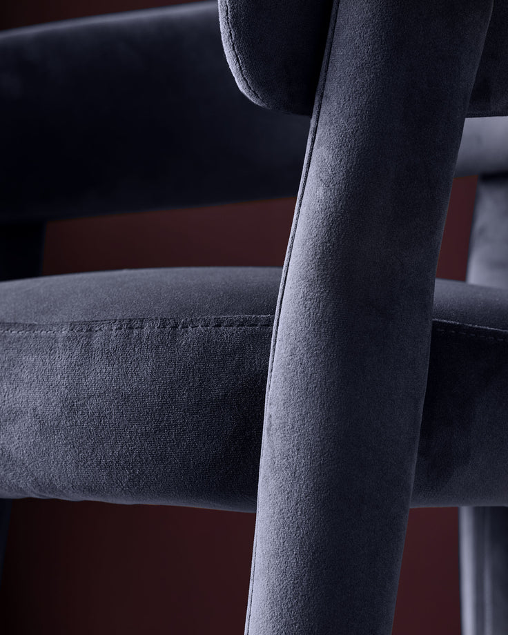 Dark navy velvet Anya bar stool, close-up of backrest and armrest showing soft fabric texture and wooden frame detail.