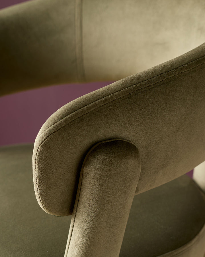 Olive green velvet bar stool with curved armrest and rolled edge detail, close-up side view.