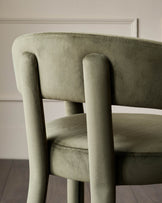 Close-up of a modern olive green chair with a velvet finish, showing the back and seat. Stylish and comfortable design.