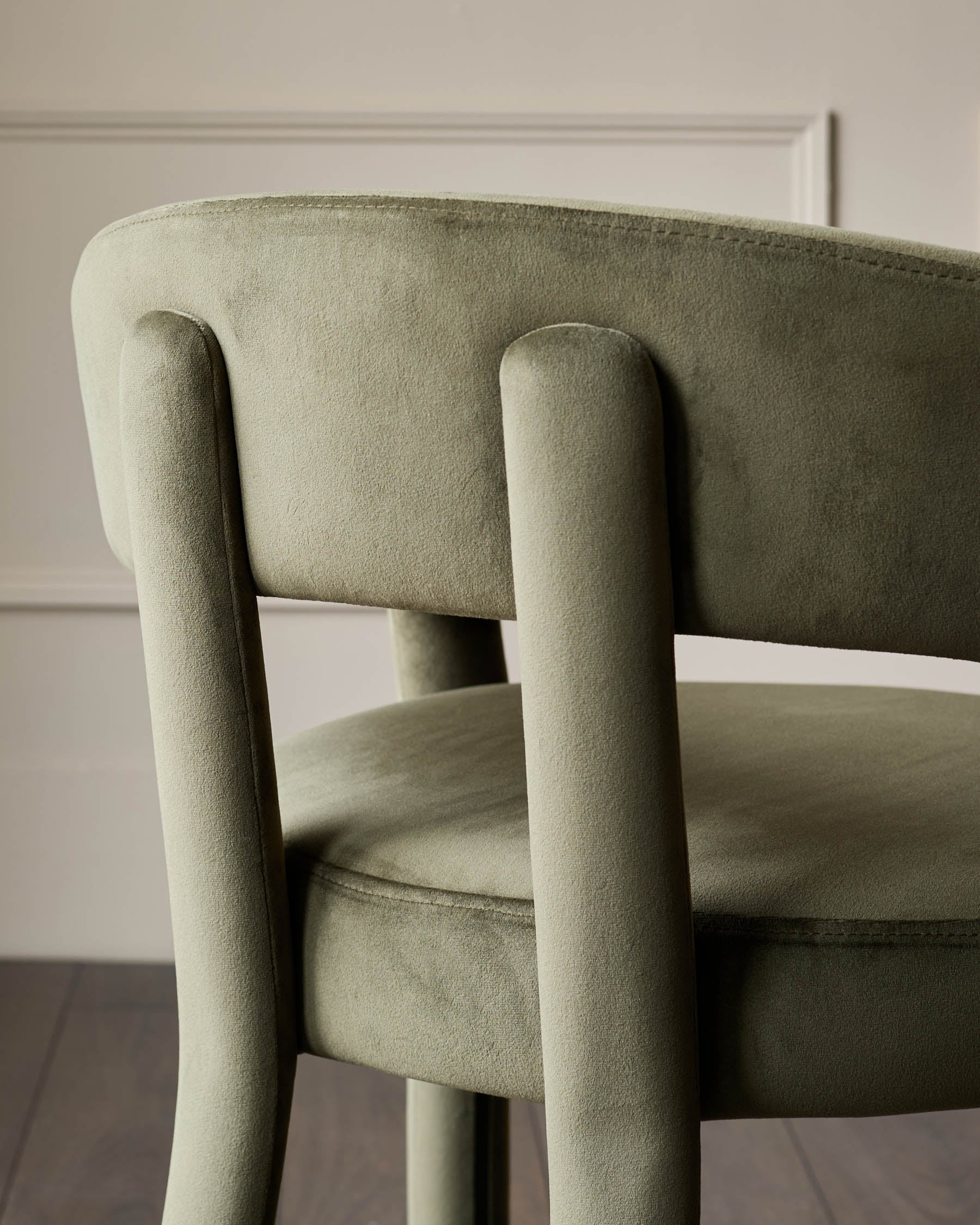 Close-up of a modern olive green chair with a velvet finish, showing the back and seat. Stylish and comfortable design.