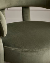 Close-up of an olive green velvet chair, highlighting the texture and detailing of the seat and backrest.