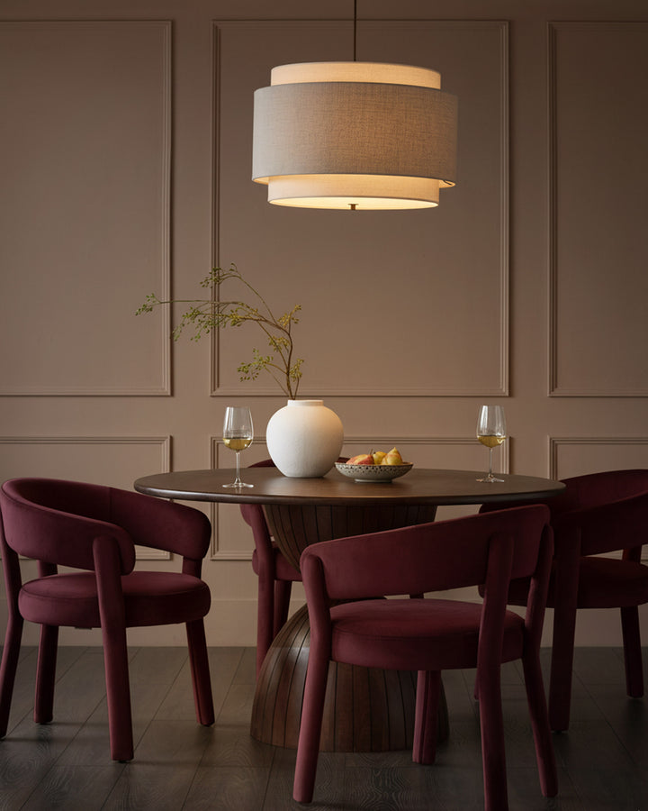 Plum velvet dining chair with curved arms and rounded backrest, shown at round table in elegant dining room setting.