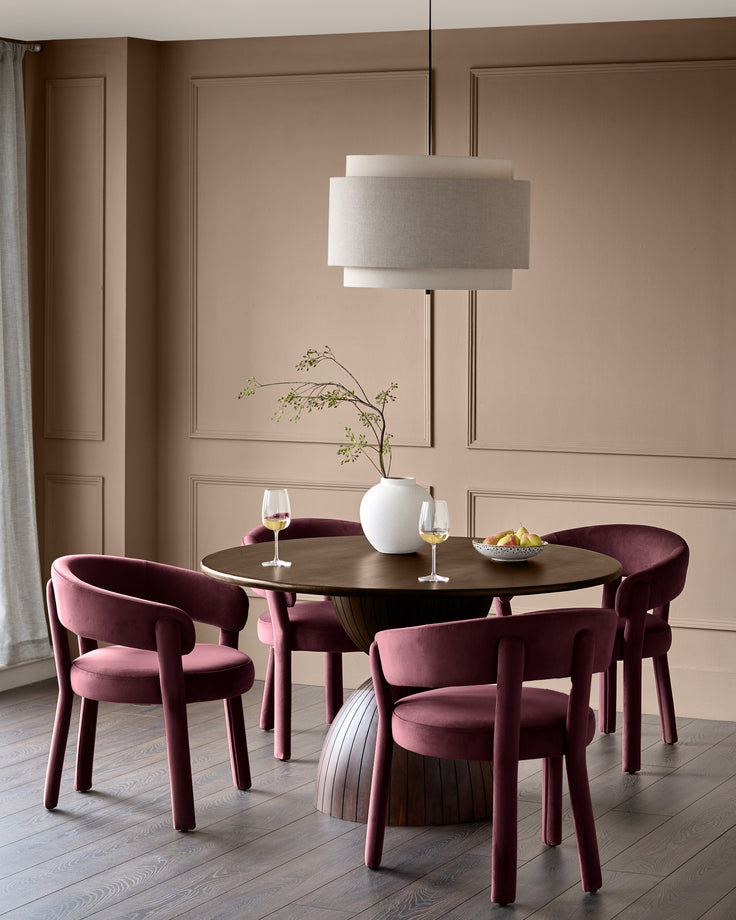 Plum velvet dining chair with curved back and cylindrical legs in an elegant dining room setting.