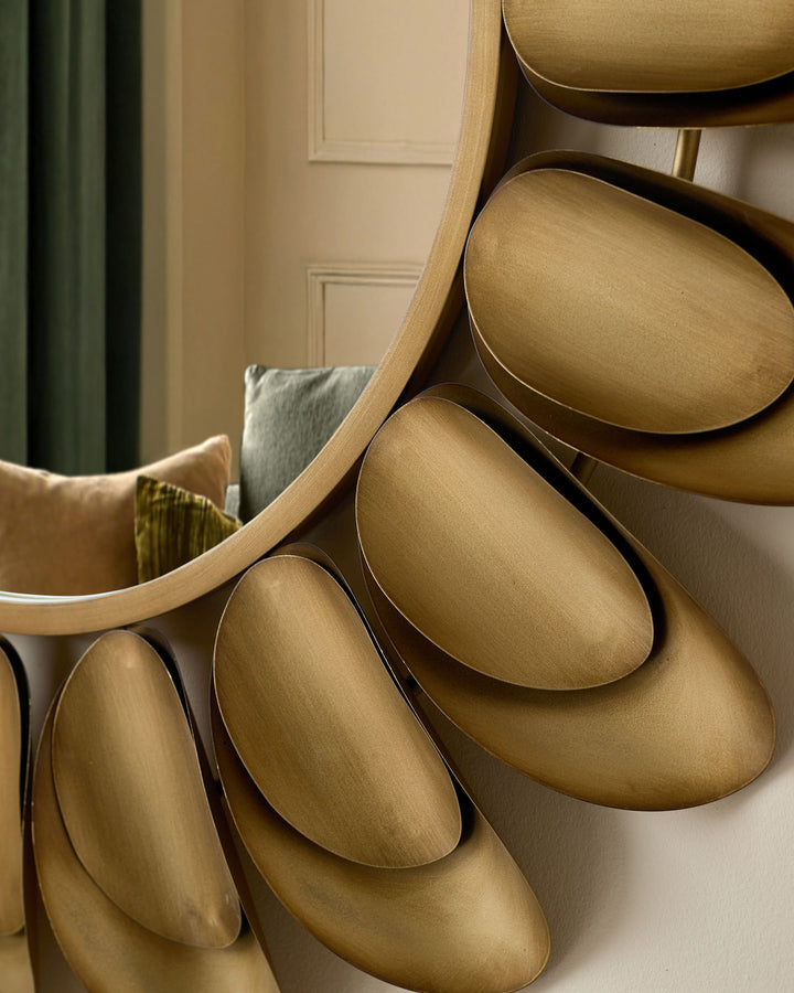 Gold round wall mirrors displayed in an interior setting, showing brushed gold finish and curved frames stacked together.
